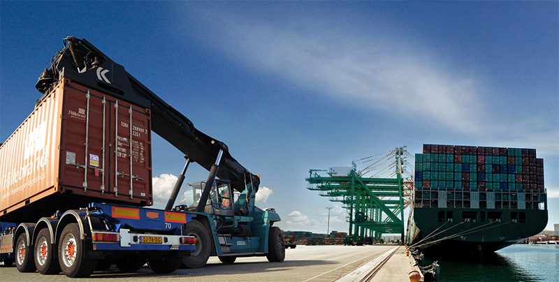 Container being loaded at a port beside a cargo ship